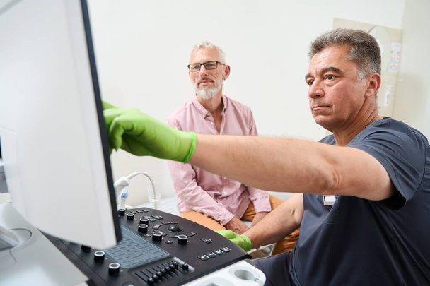 Doctor consults an elderly patient in an ultrasound room using modern equipment - Photo, Image