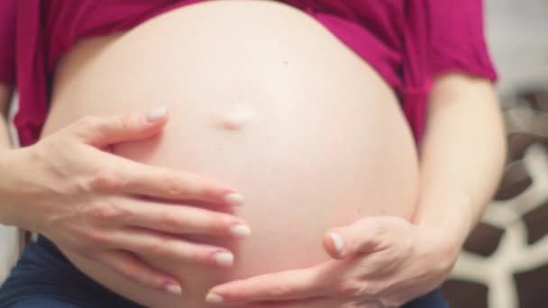 A mulher grávida segura as mãos no estômago. Terceiro trimestre. Gravidez. À espera de um milagre. Maternidade - Filmagem, Vídeo