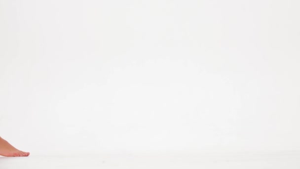 pernas nuas femininas andando sobre um fundo branco. câmara lenta. Imagens 4k de alta qualidade - Filmagem, Vídeo
