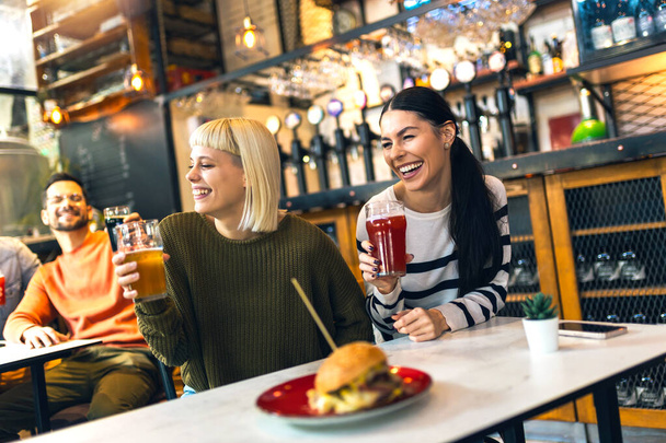 Sorridente giovani amici bere birra artigianale in pub - Foto, immagini