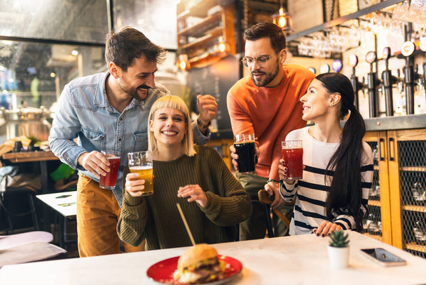 Усміхнені молоді друзі п'ють крафтове пиво в пабі
 - Фото, зображення