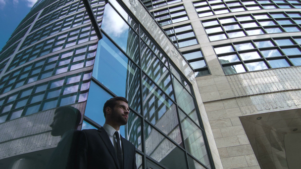 Businessman standing by the skyscraper - Filmati, video