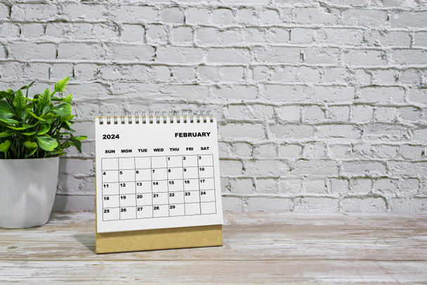 Λευκό Φεβρουάριος 2024 ημερολόγιο στο γραφείο ξύλινο γραφείο με γλάστρα φυτό. 2024 έννοια του νέου έτους - Φωτογραφία, εικόνα