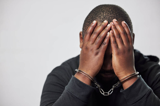 Handcuffs, criminal and hands of black man with stress, worry and anxiety in police station for crime. Law, mockup and male person with chains for investigation, theft and fraud suspect in prison. - Photo, Image