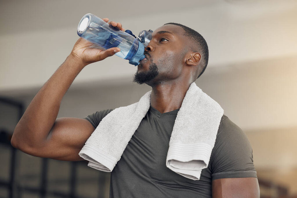 Fitness, fitnessruimte en zwarte man drinkwater na training of training voor hydratatie, gezondheid of wellness. Sterke, gezonde en Afrikaanse atleet genieten van een drankje na intensieve oefening in het sportcentrum - Foto, afbeelding