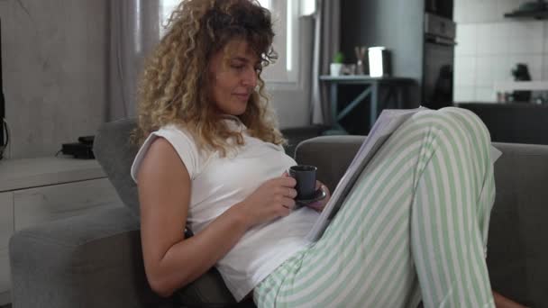 una mujer caucásica estudio en casa leer y preparar examen personas reales tienen documentos en papel o correo mientras se sientan en el sofá cama  - Metraje, vídeo