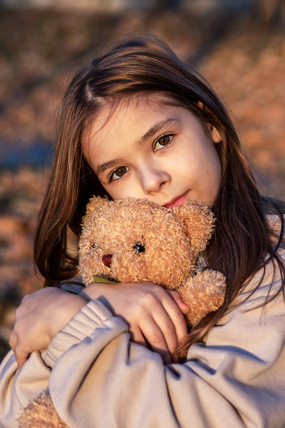 Girl hugging teddy bear and looking at camera. - Photo, Image