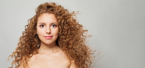 Positive friendly woman with wavy hair and natural makeup. Fashion model with long curly hairstyle and fresh clear skin posing on white background - Photo, Image