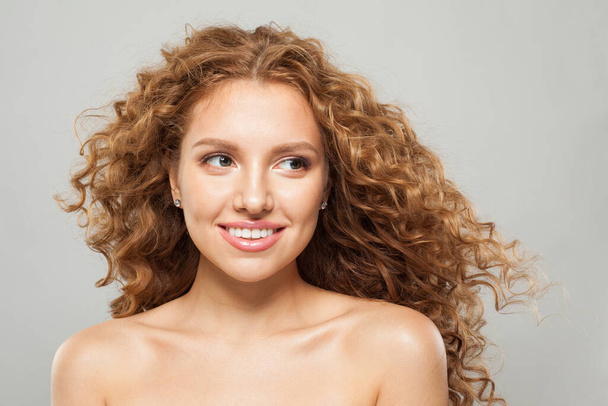 完璧な若い女性の赤毛ファッションモデル 長い自然な健康な茶色のカーリーの髪と白い背景に脇に見えるかわいい笑顔. ヘアケア,ヘアケア,ウェルネス,化粧品コンセプト - 写真・画像