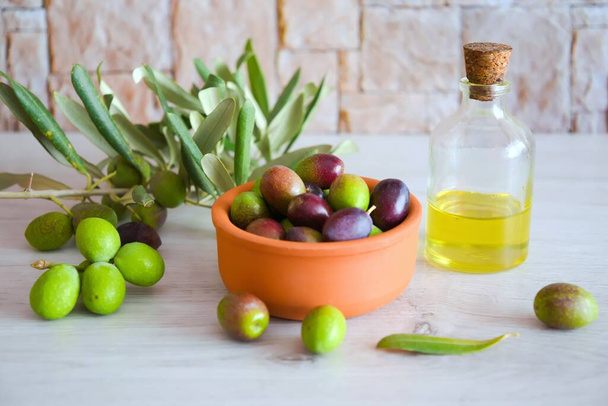 Background of unripe green olives and olive oil in a wooden plate - Photo, Image