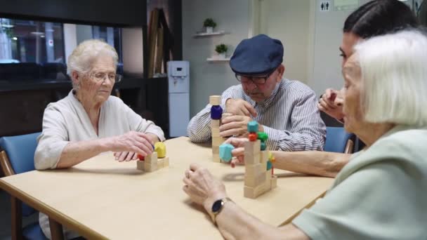 Video van verpleegkundige en oudere mensen oplossen puzzel vaardigheid spel samen in een verpleeghuis - Video