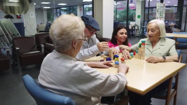 Video einer zarten Krankenschwester, die älteren Menschen hilft, Geschicklichkeitsspiele im Pflegeheim zu lösen - Filmmaterial, Video