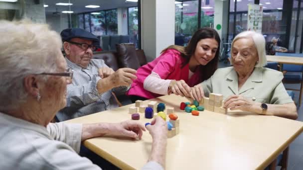 Wideo z pielęgniarką i osobami starszymi rozwiązującymi gry zręcznościowe w domu opieki - Materiał filmowy, wideo