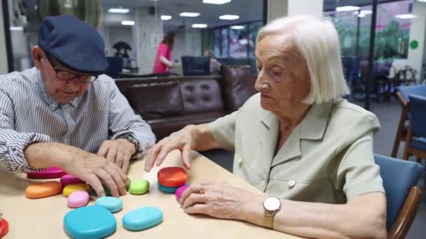 Wideo z drzewnymi starszymi ludźmi rozwiązującymi gry z umiejętnościami mózgu w domu opieki - Materiał filmowy, wideo