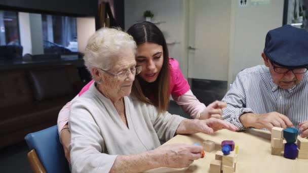 Video einer Krankenschwester, die alten Menschen hilft, Geschicklichkeitsspiele in einem Pflegeheim zu lösen - Filmmaterial, Video