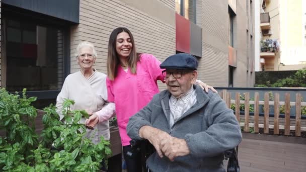 Video einer Krankenschwester und alter Menschen, die in einem städtischen Garten in einem Pflegeheim singen und tanzen - Filmmaterial, Video