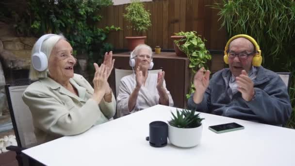 Videó három idős emberről, akik élvezik a zenehallgatást mobiltelefonnal egy idősek otthonában - Felvétel, videó
