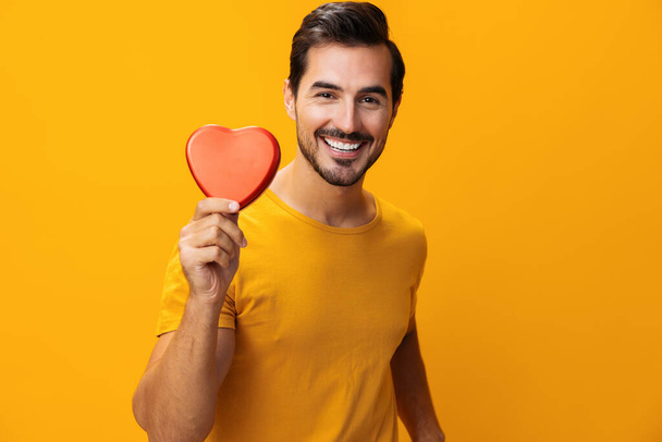 Hombre mano forma San Valentín sonriente romance estudio corazón fondo concepto romántico retrato rojo amarillo amor símbolo regalo caja feliz - Foto, imagen