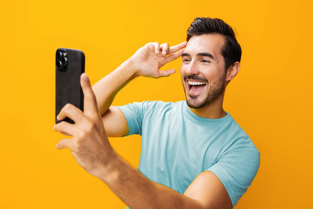 Hombre apuntando comunicación estilo de vida tecnología copia espacio teléfono móvil gafas estudio mensaje de negocios smartphone retrato ciberespacio amarillo feliz sorpresa teléfono sonriendo - Foto, Imagen