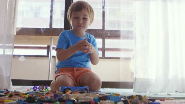 Un niño sentado en el suelo rodeado de juguetes - Imágenes, Vídeo