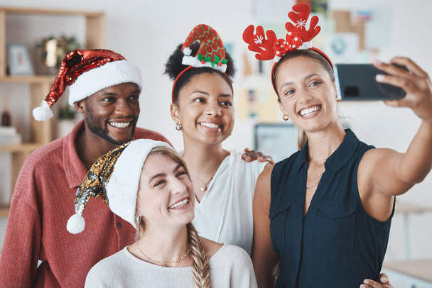 Kerstfeest, telefoon selfie en zakenmensen in de viering van feestelijke vakantie. Diversiteit, glimlach en gelukkig werk vrienden vieren op 5g mobiele, sociale media foto post of happy office geheugen. - Foto, afbeelding