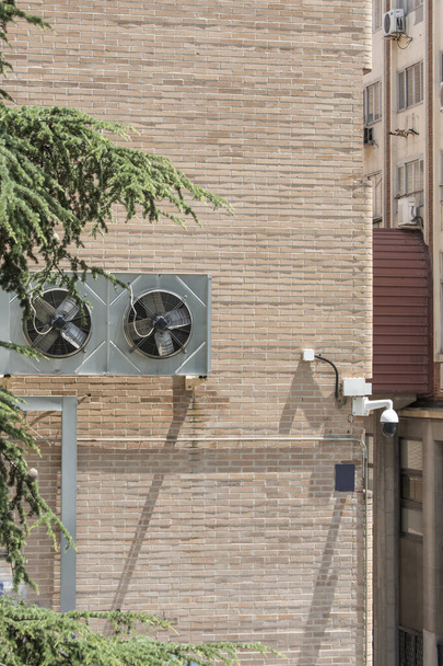 Камера спостереження та вентилятори кондиціонування на стіні цегляної будівлі - Фото, зображення
