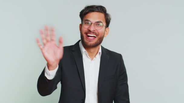 Індійський бізнесмен посміхається доброзичливо на камеру, махаючи руками жестикулюючи привіт привітання або прощаючись з запрошеним гостинним виразом. Арабська індуїстська людина ізольована на сірому студійному фоні - Кадри, відео