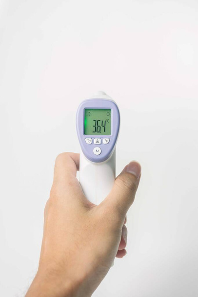 mano sosteniendo termómetro infrarrojo digital aislado sobre fondo blanco. con espacio de copia - Foto, imagen