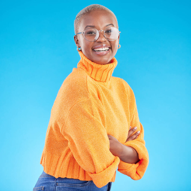 Portrait, happy and black woman with glasses, arms crossed and studio isolated on a blue background. Face, confident nerd and smile for fashion, style and person from South Africa in casual clothes. - Φωτογραφία, εικόνα