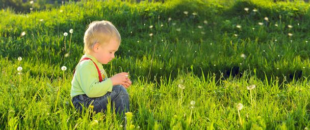 Kleine jongen op voorjaar groen gras achtergrond - Foto, afbeelding
