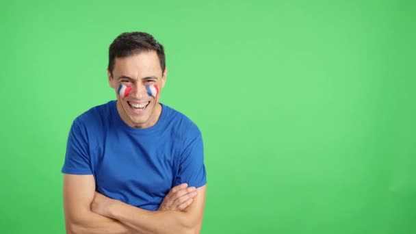 Video en estudio con el croma de un hombre de pie con la bandera francesa pintado en la cara sonriendo con los brazos cruzados - Metraje, vídeo