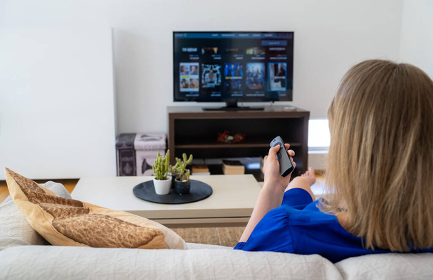 Vrouw kijkt content op haar Smart TV thuis. - Foto, afbeelding