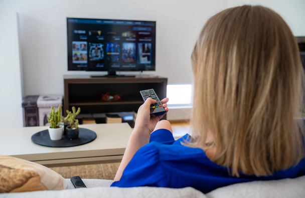 Γυναίκα παρακολουθεί περιεχόμενο στην Smart TV της στο σπίτι. - Φωτογραφία, εικόνα