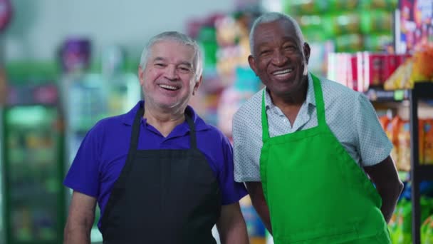 Happy diverse senior employees standing in supermarket aisle. Caucasian manager engaging with workforce teamwork with African American colleague - Footage, Video