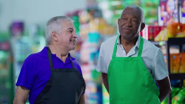 Happy diverse senior talking and smiling standing in supermarket aisle. Caucasian manager engaging with workforce teamwork with African American colleague - Footage, Video