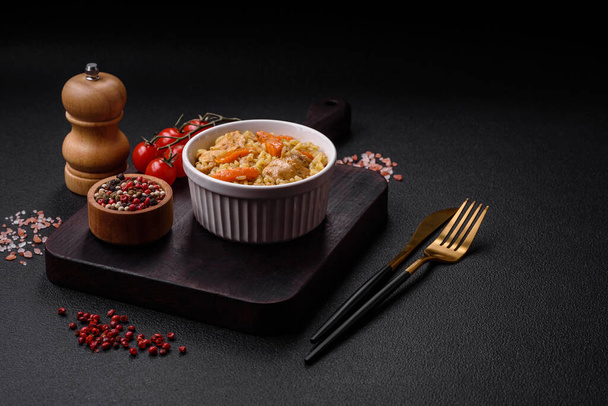 Delicious Uzbek pilaf with chicken, carrots, barberry, spices and herbs on a dark concrete background - Photo, Image