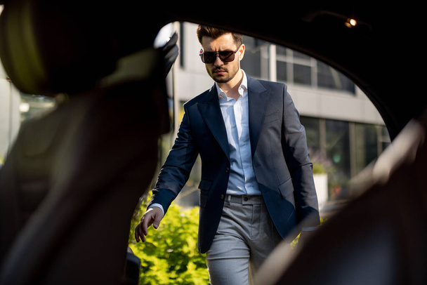 Schöner Geschäftsmann, der auf dem Rücksitz eines Luxus-Taxis ins Auto steigt. Fahrzeugtransport und Business-Lifestyle-Konzept - Foto, Bild