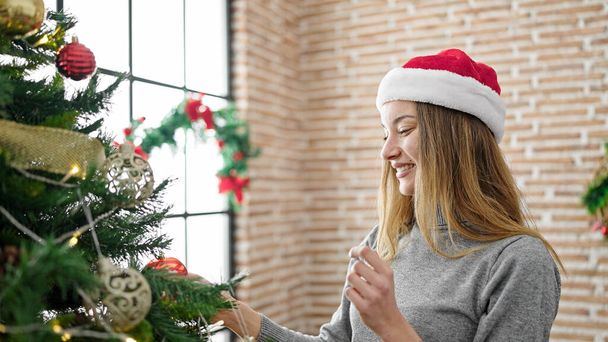 Jovem mulher caucasiana decorando árvore de Natal em casa - Foto, Imagem