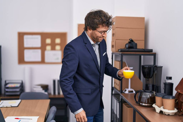 Молодий іспаномовний чоловік бізнесмен п'є каву в офісі
 - Фото, зображення