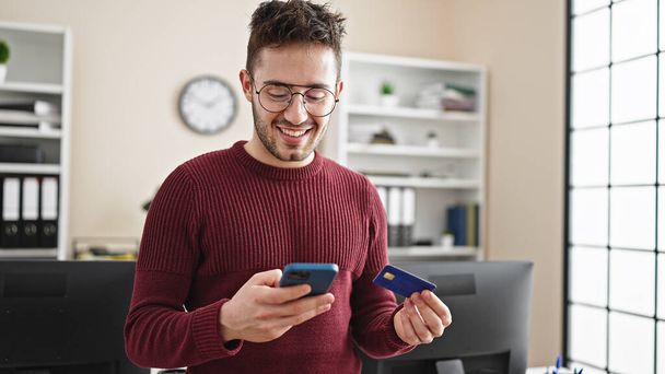 Young hispanic man business worker shopping with smartphone and credit card at office - Photo, Image