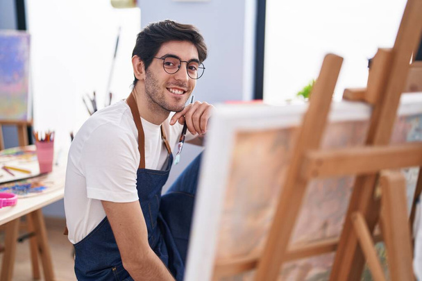 Mladý hispánec muž umělec se usmívá sebevědomě vypadající remíza na výtvarné studio - Fotografie, Obrázek