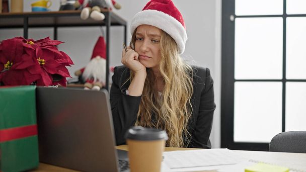 Mujer joven rubia trabajadora de negocios celebrando la Navidad trabajando estresada en la oficina - Foto, imagen