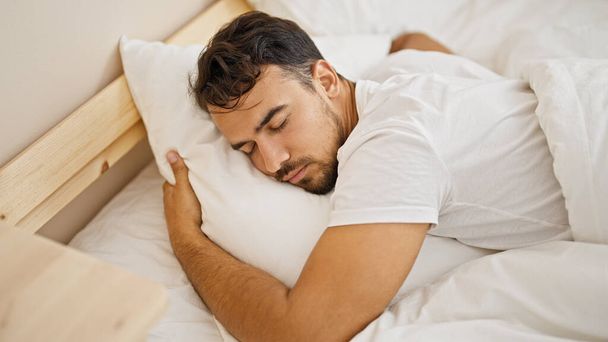 Junger hispanischer Mann umarmt auf Bett liegendes Kissen und schläft im Schlafzimmer - Foto, Bild