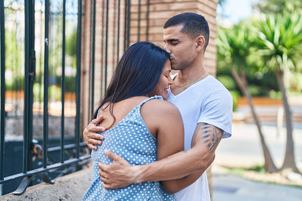 Hombre y mujer pareja sonriendo confiado abrazándose en la calle - Foto, imagen