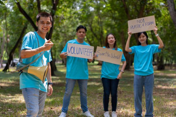 Mutlu Asyalı genç öğrenciler parkta temizlik için bir kampanya tabelası tutuyorlar, çevre koruma kavramı, geri dönüşüm, sürdürülebilirlik için yardım.. - Fotoğraf, Görsel
