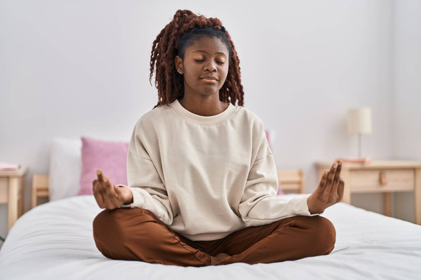 Donna afroamericana che fa esercizio di yoga seduto sul letto in camera da letto - Foto, immagini