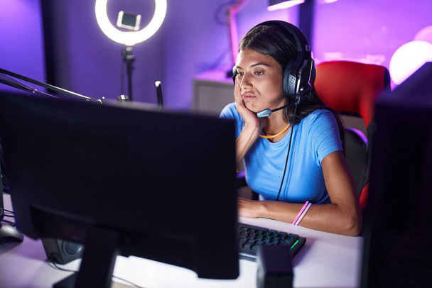 Brunette νεαρή γυναίκα παίζει βιντεοπαιχνίδια σκέφτεται κουρασμένος και βαριέται με προβλήματα κατάθλιψης με σταυρωμένα χέρια.  - Φωτογραφία, εικόνα