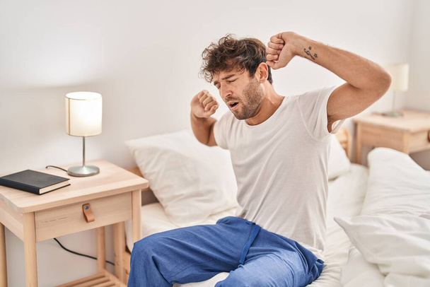 Young man waking up stretching arms at bedroom - Fotoğraf, Görsel