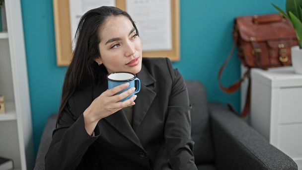 Genç, güzel, İspanyol bir iş kadını ofiste kahve içiyor. - Fotoğraf, Görsel