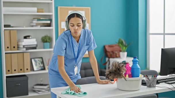 African american woman professional cleaner cleaning table listening to music at the office - Photo, Image